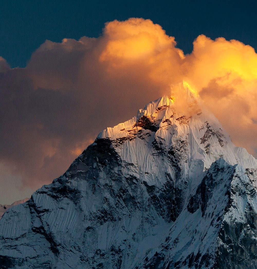 Alpenglow light breaking through clouds over a mountain peak